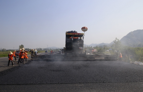 2019年8月，宜春經(jīng)開區(qū)S311路面攤鋪現(xiàn)場，工友們輔助路面兩側(cè)的分料、補窩等作業(yè)