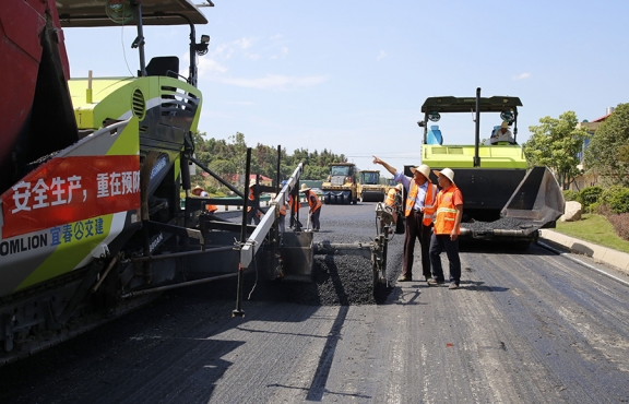 攤鋪機、壓路機等設(shè)備緊張有序運行，高達(dá)170℃的瀝青混合料炙烤著公路人